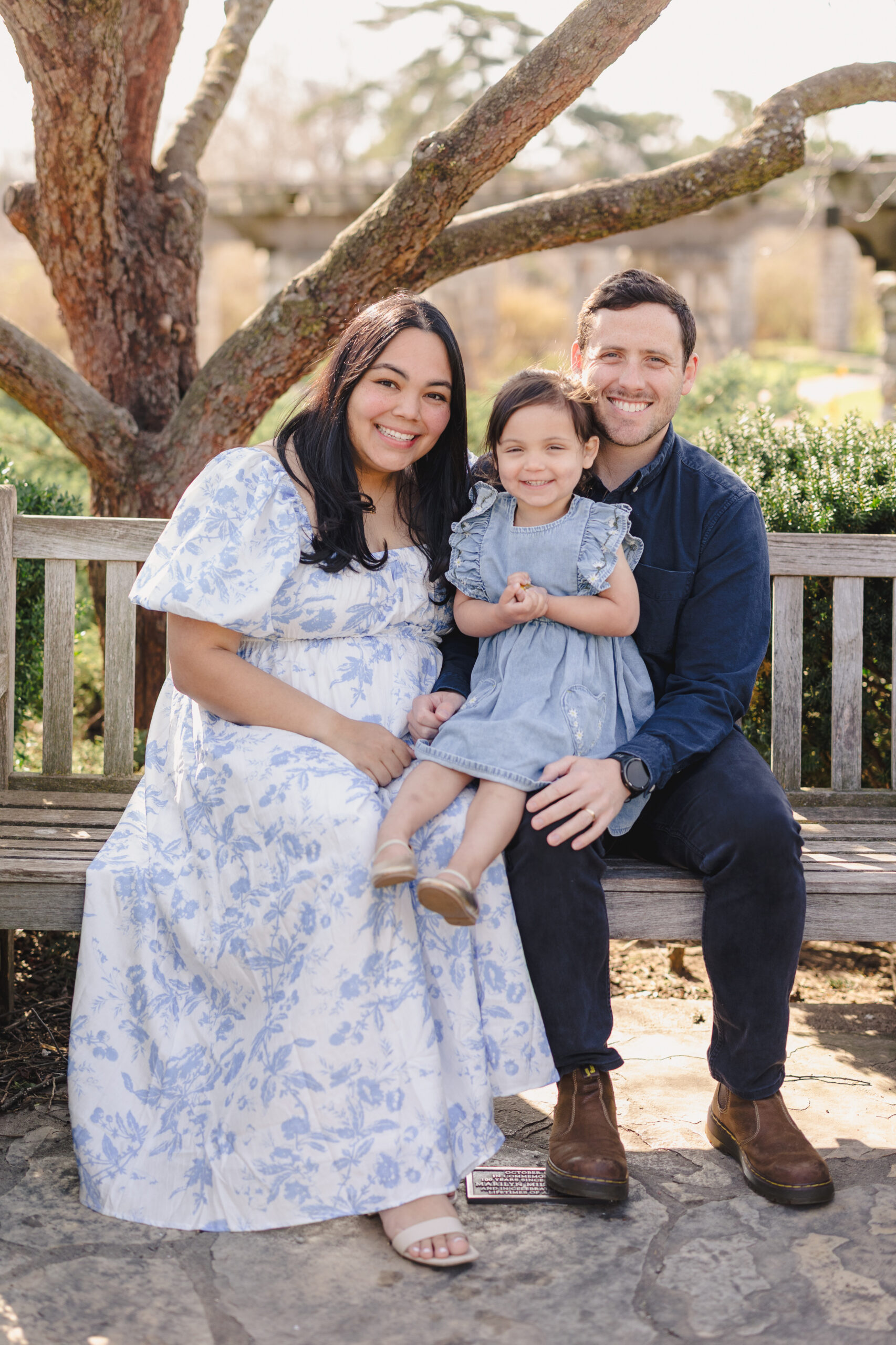 a family sitting on a bench in loose park in kansas city taking family photos in the spring 