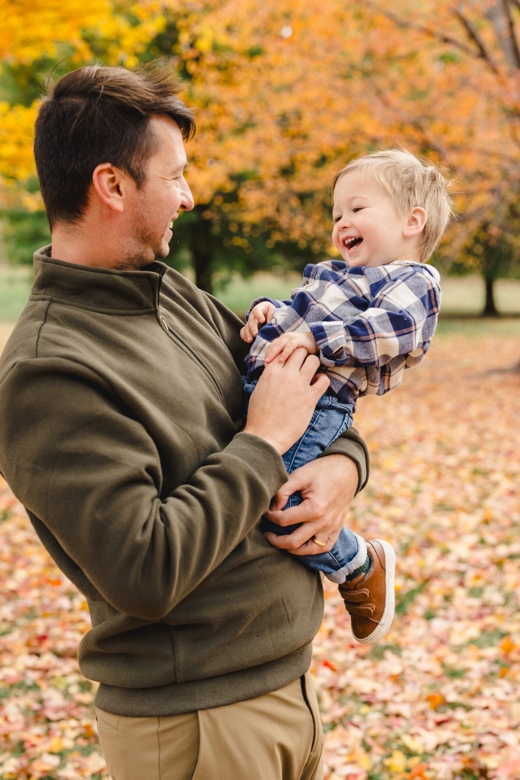 a father holding his son in a park during the fall 