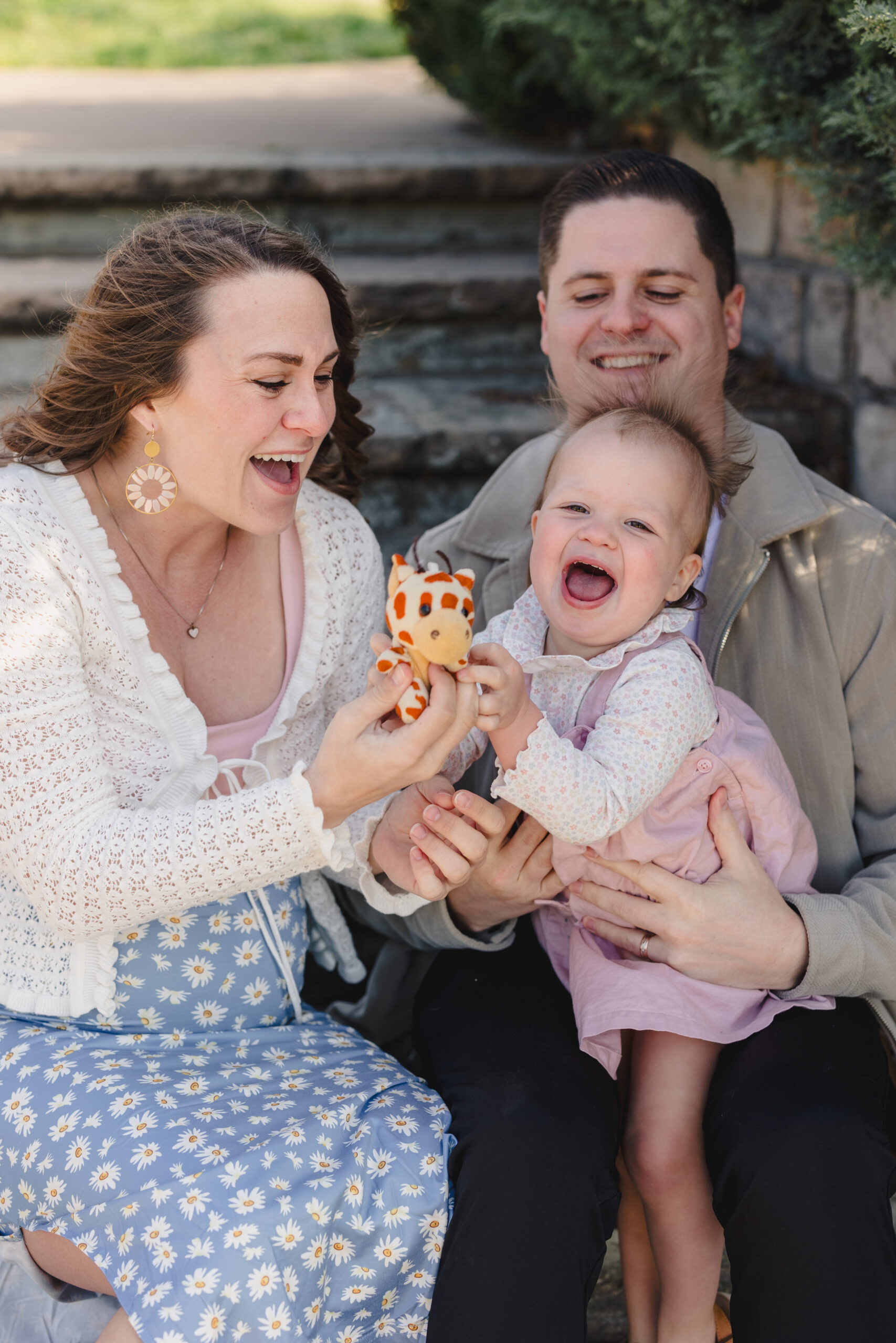 a mothe and father sitting on steps holding their daughter 