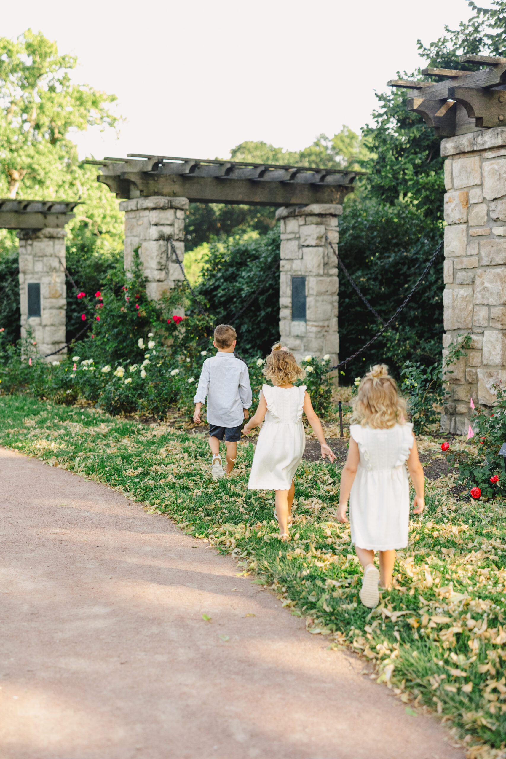 three children wandering in the grass at loose park 