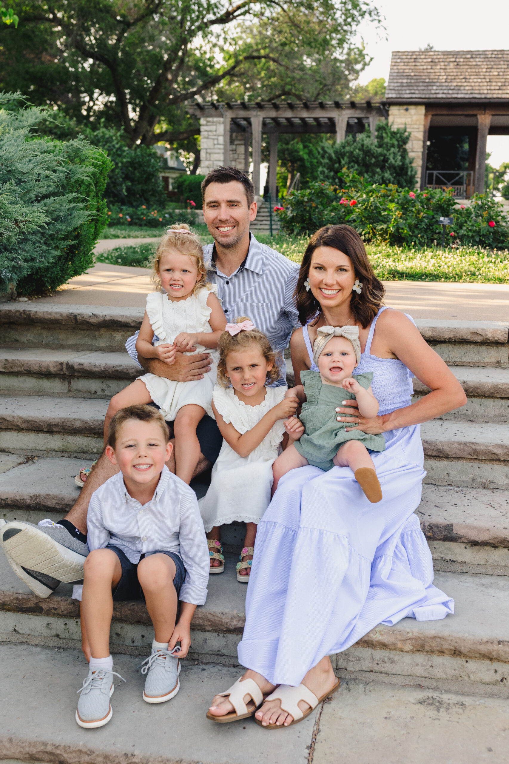 a family sitting on steps in loose park taking a family photo together in the summer 