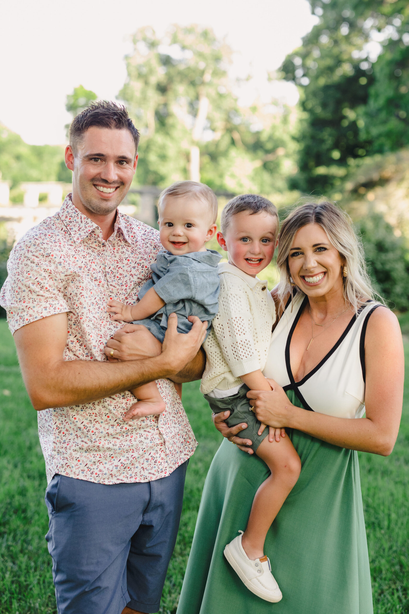 a mothe and father taking photos with their two sons in a park