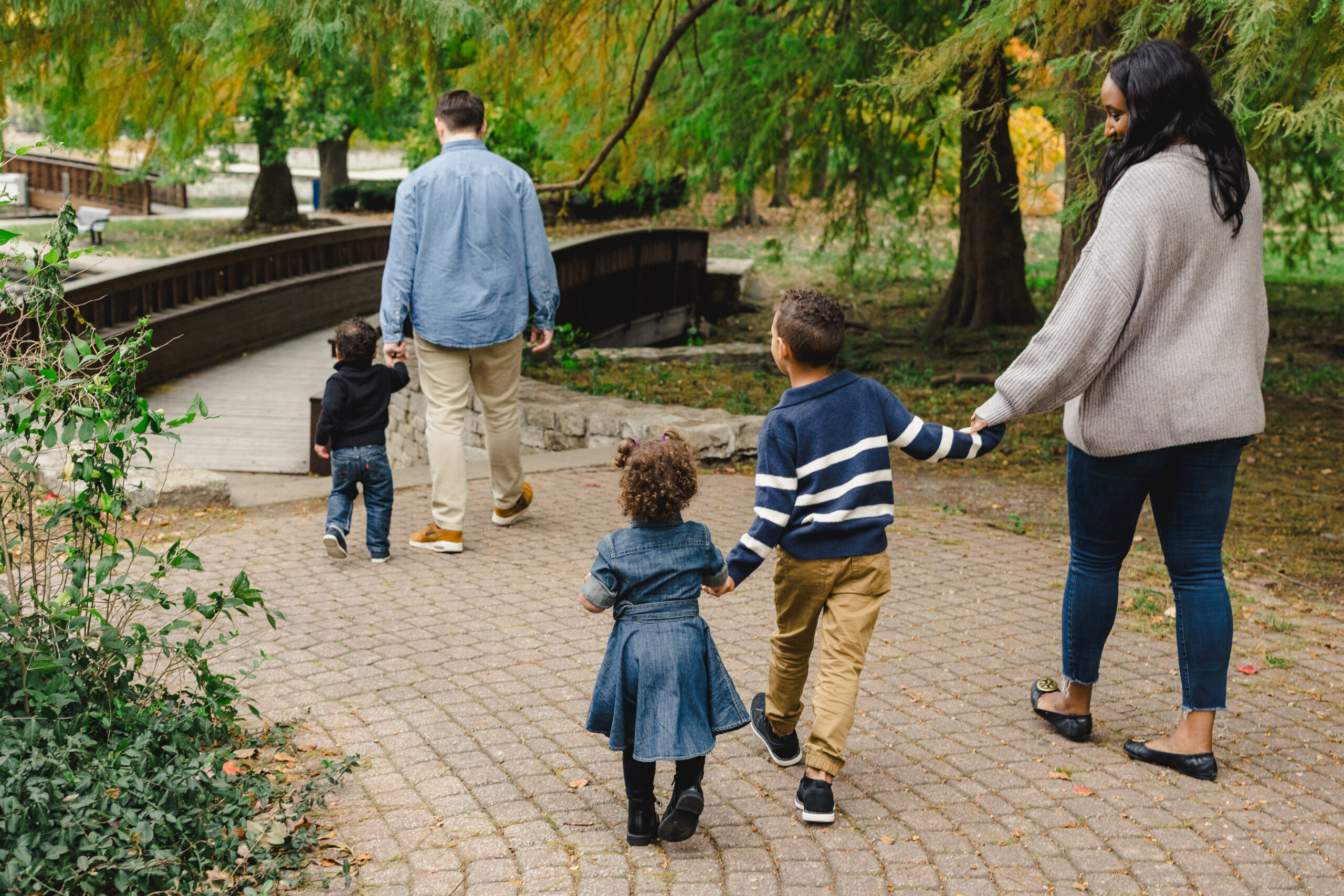 a family walking together and holding hands to the bridge in loose park 