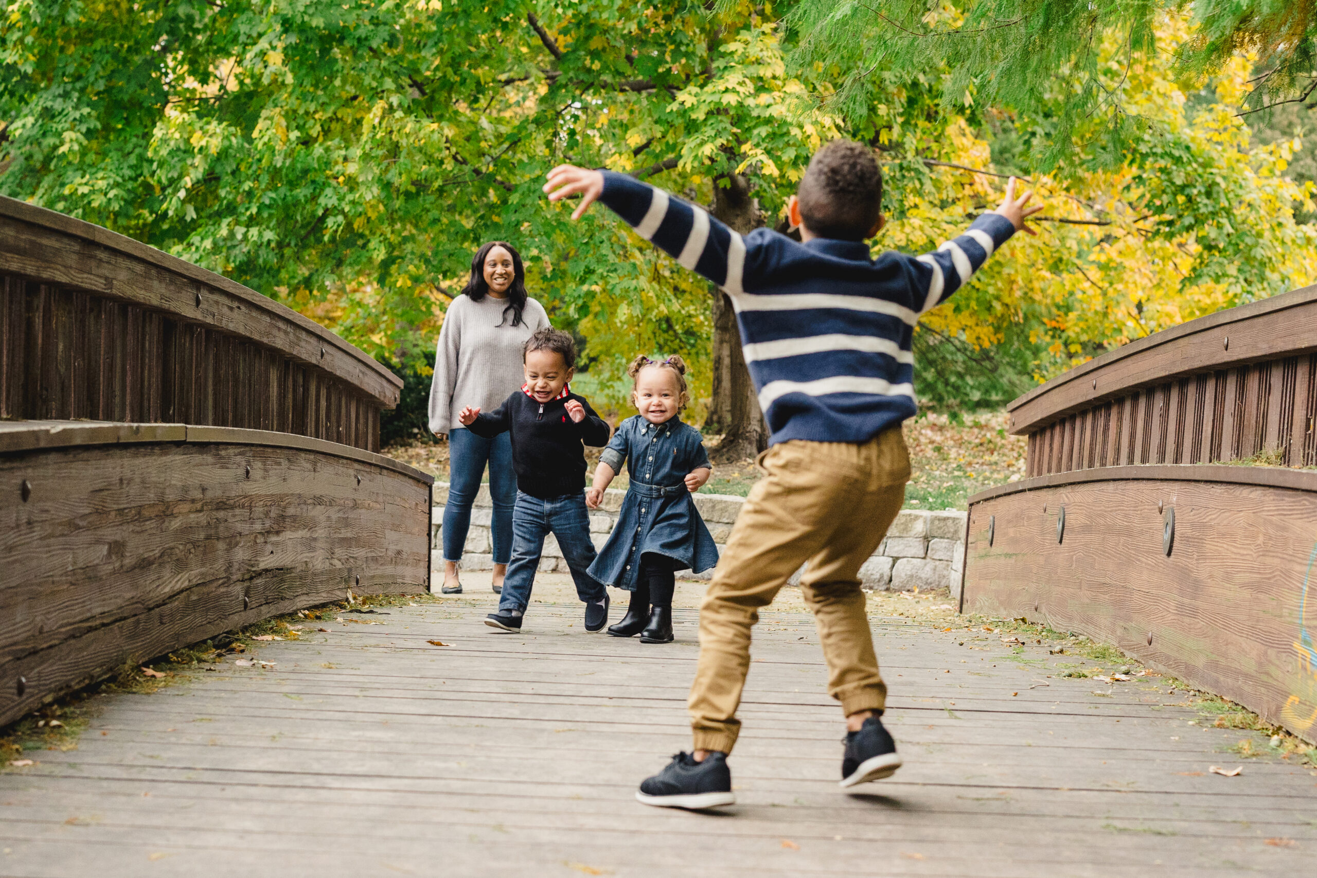 three siblings playing with each other on the bridge in loose park 