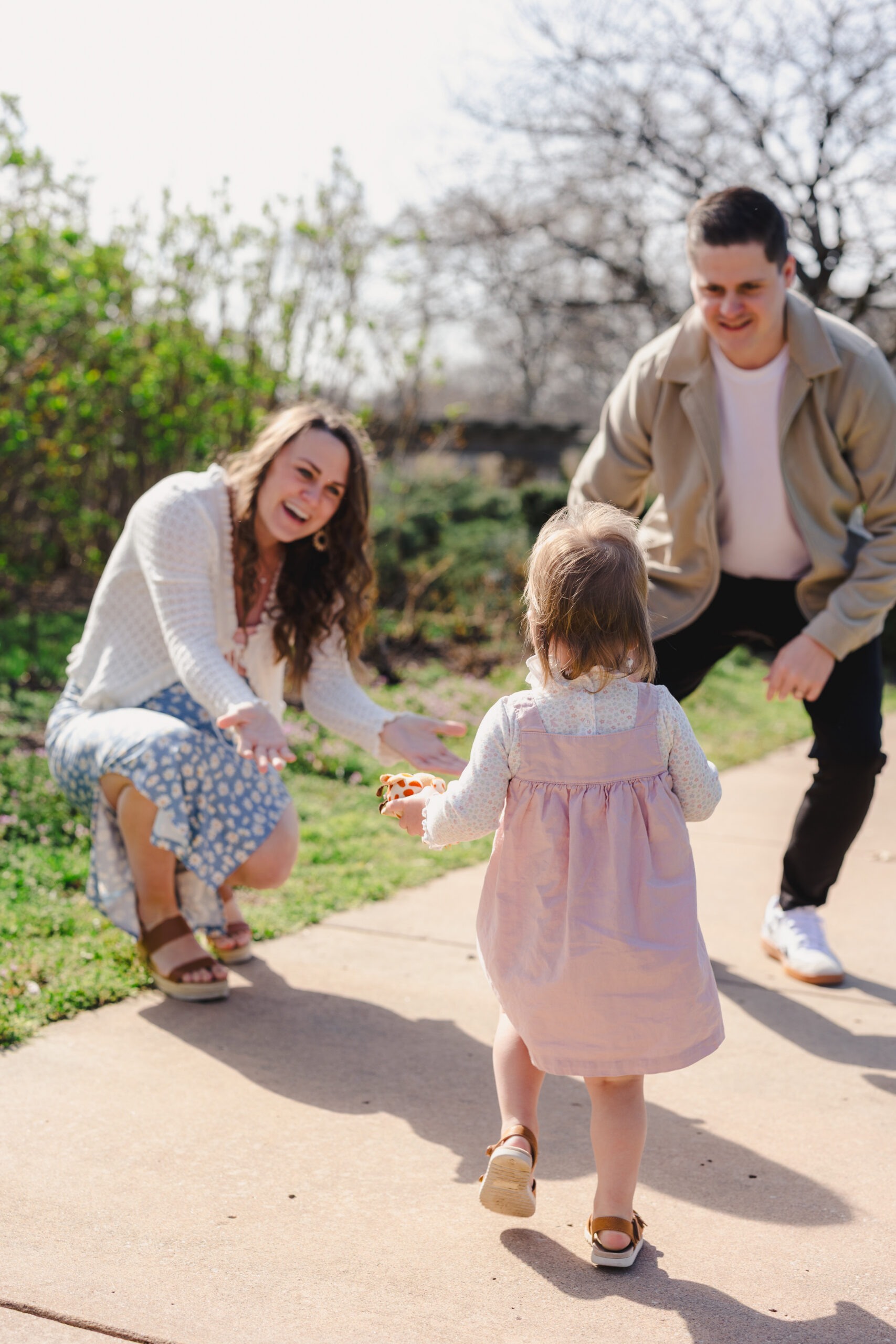 a mother and father playing with their daughter in a park 