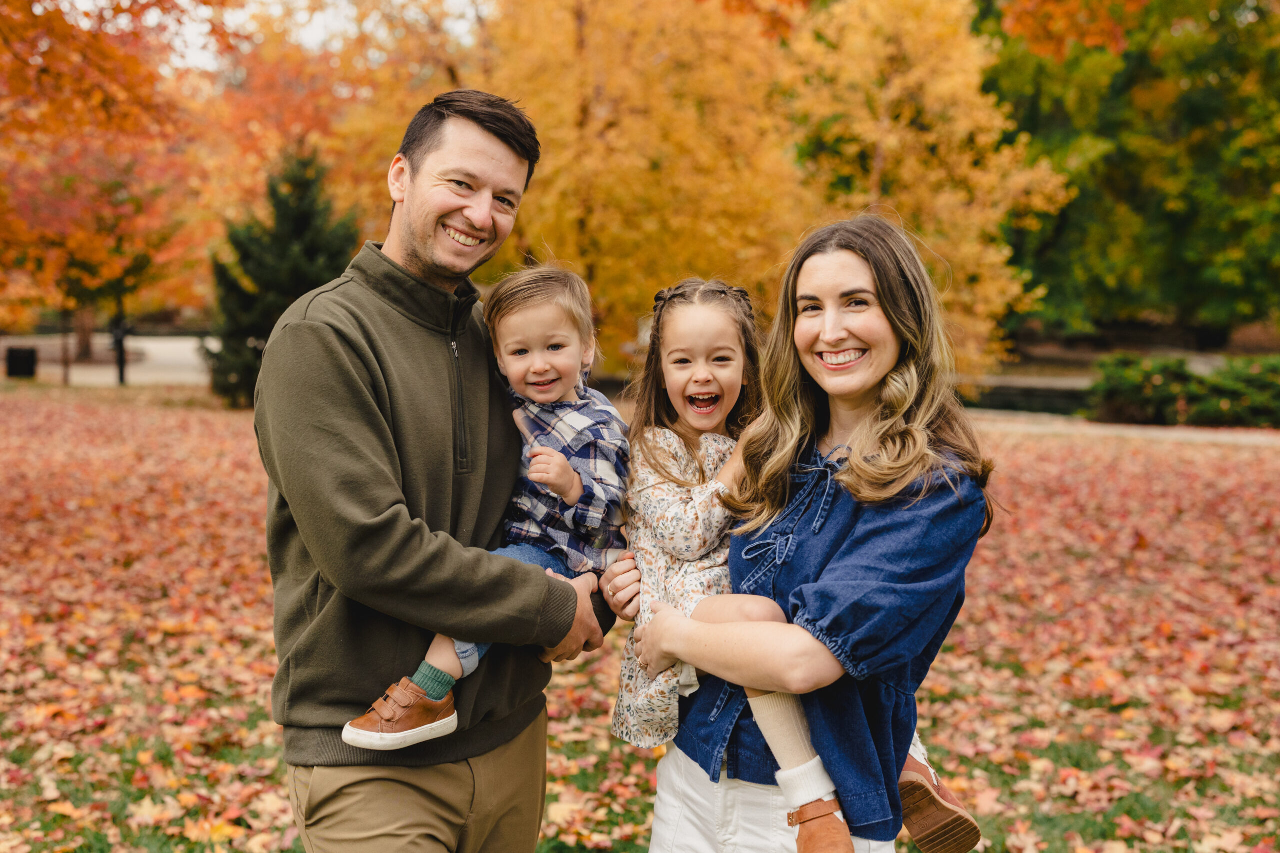 a mother and father holding their two children in loose park taking fall family photos