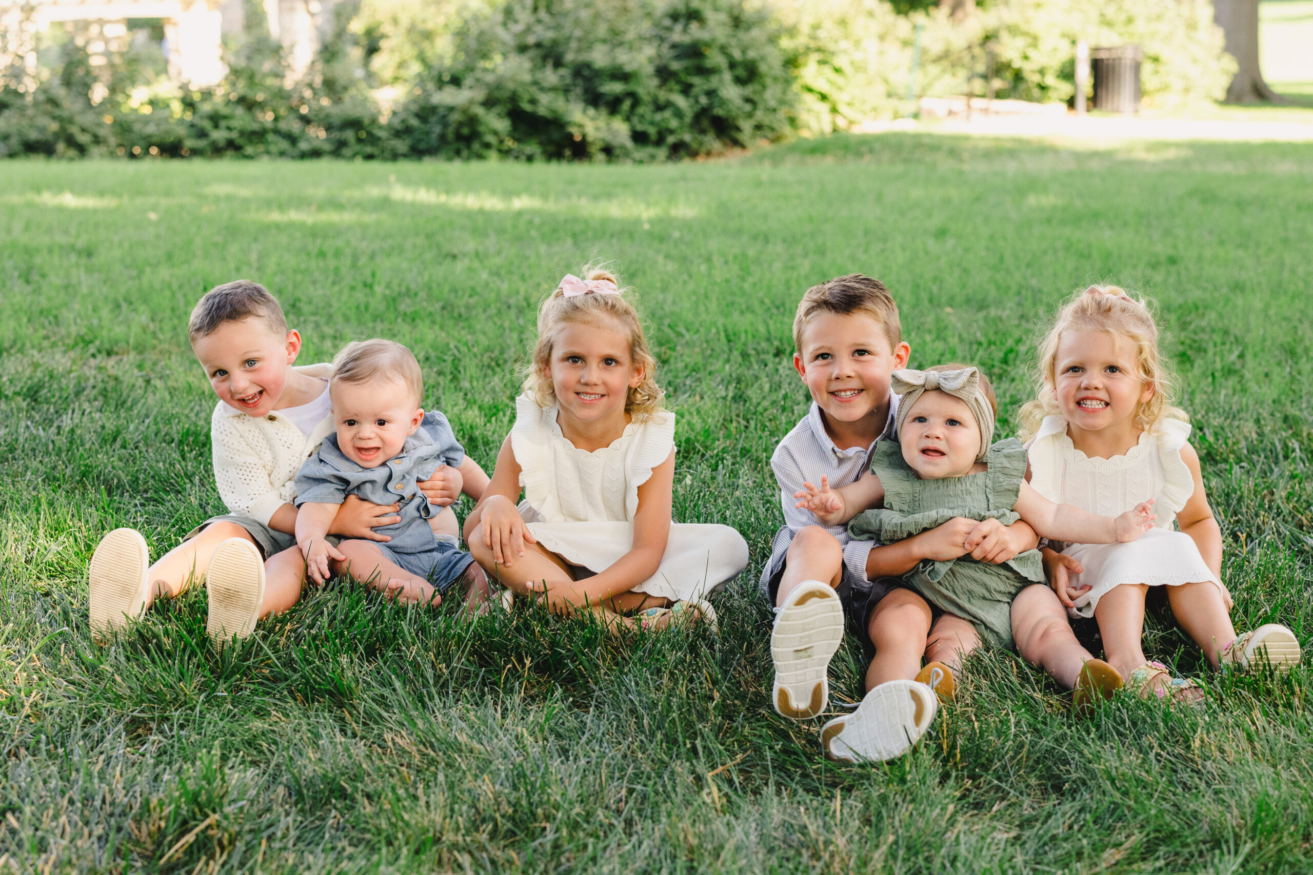 a group of grandchildren sitting on the grass together 