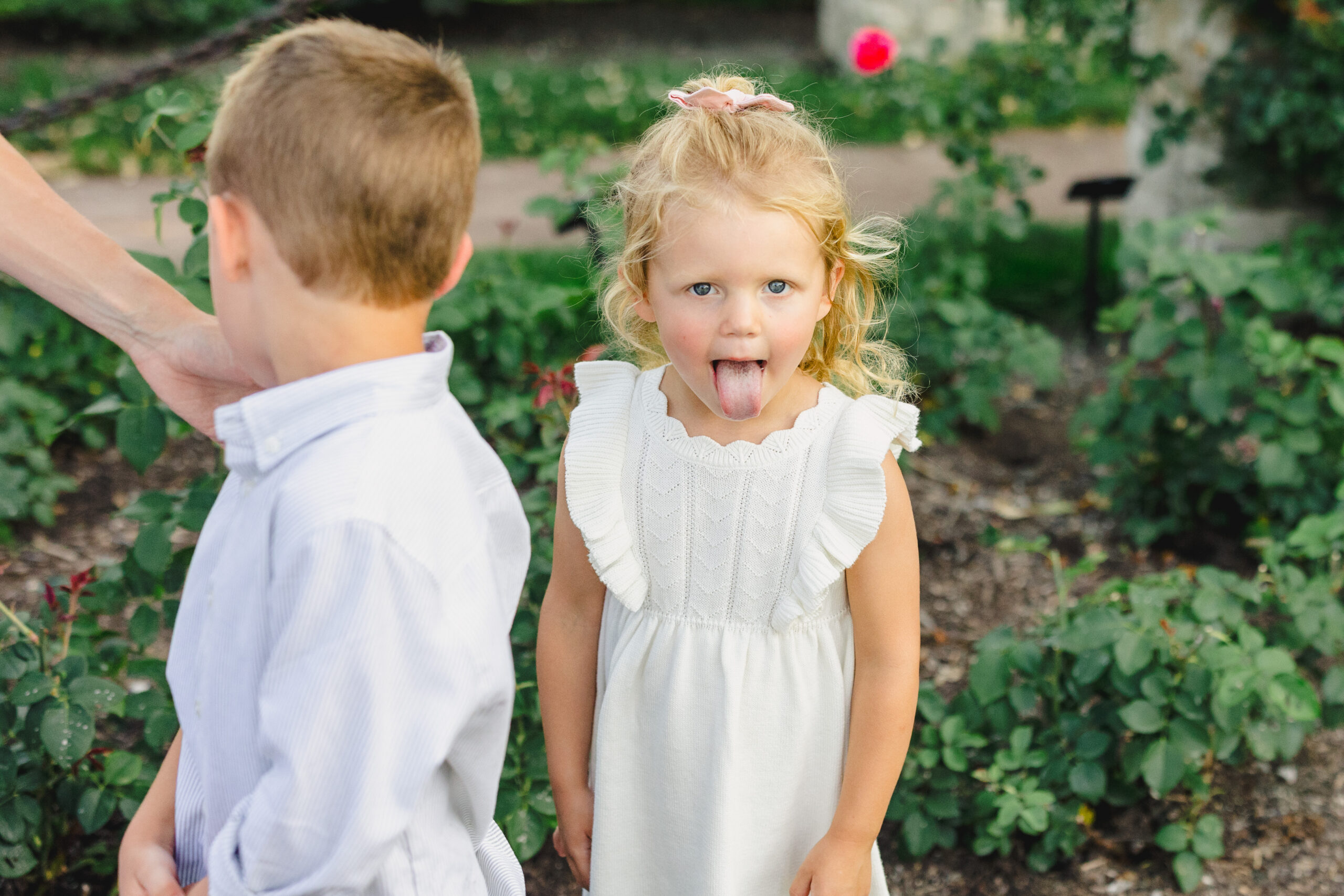 a young girl sticking out her tounge next to the rose garden 