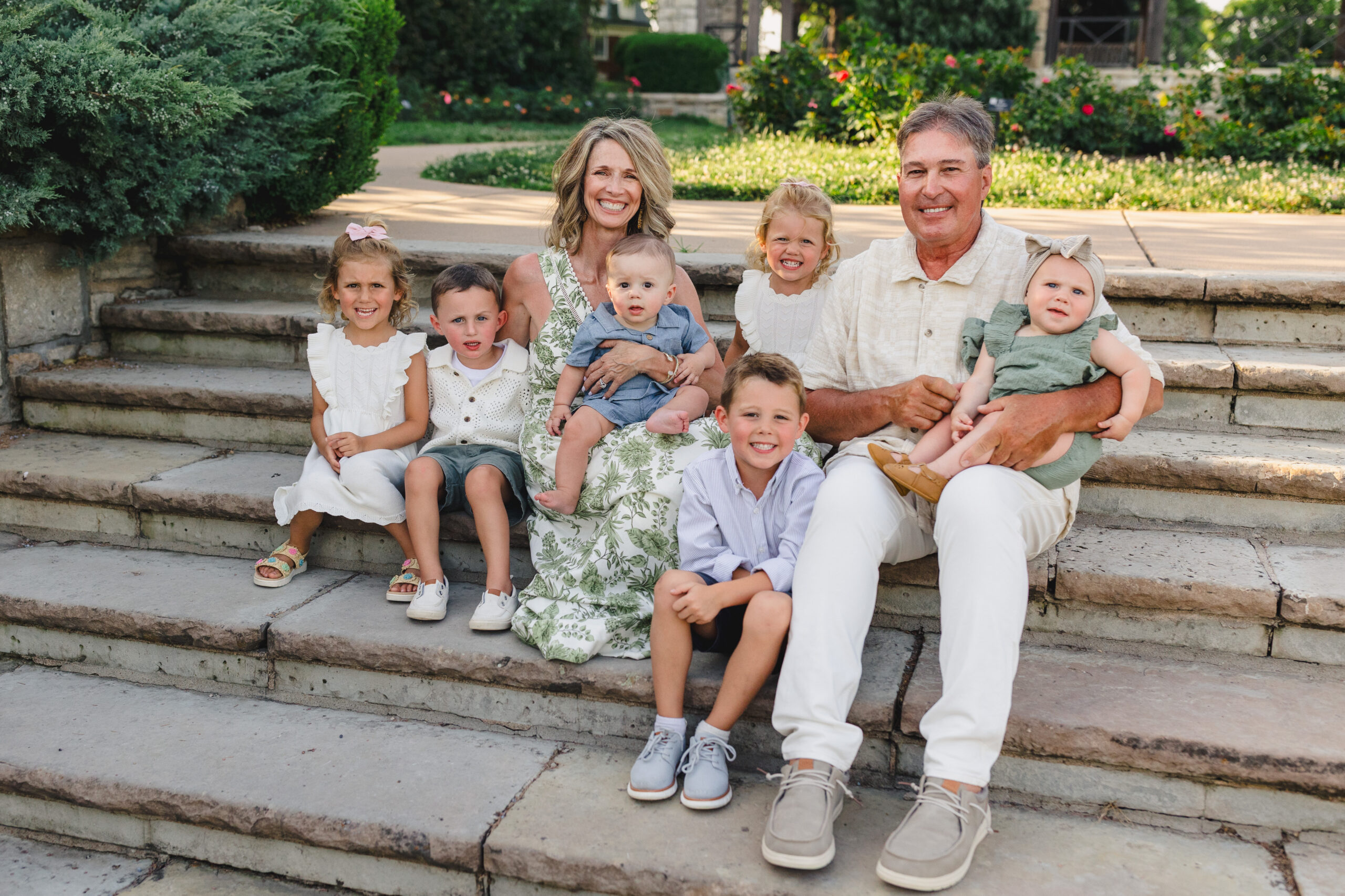 a grandma and grandpa sitting on stone steps with their grandchildren 