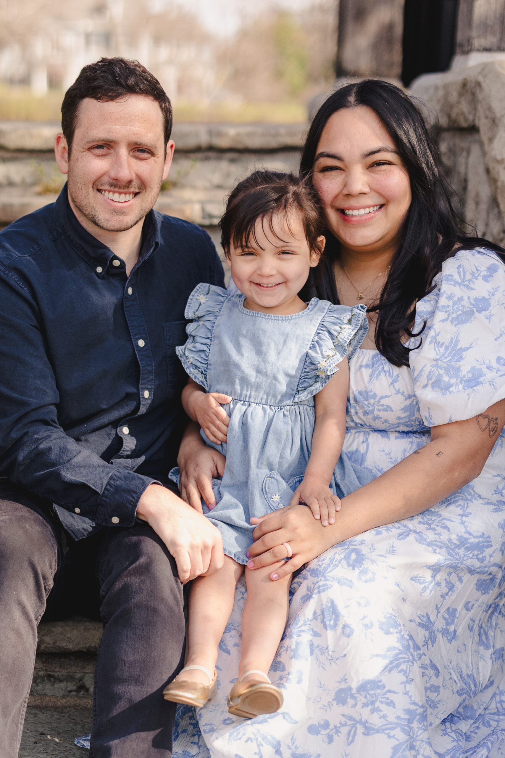 a mother, father, and daughter taking family photos at loose park in kansas city in the spring 