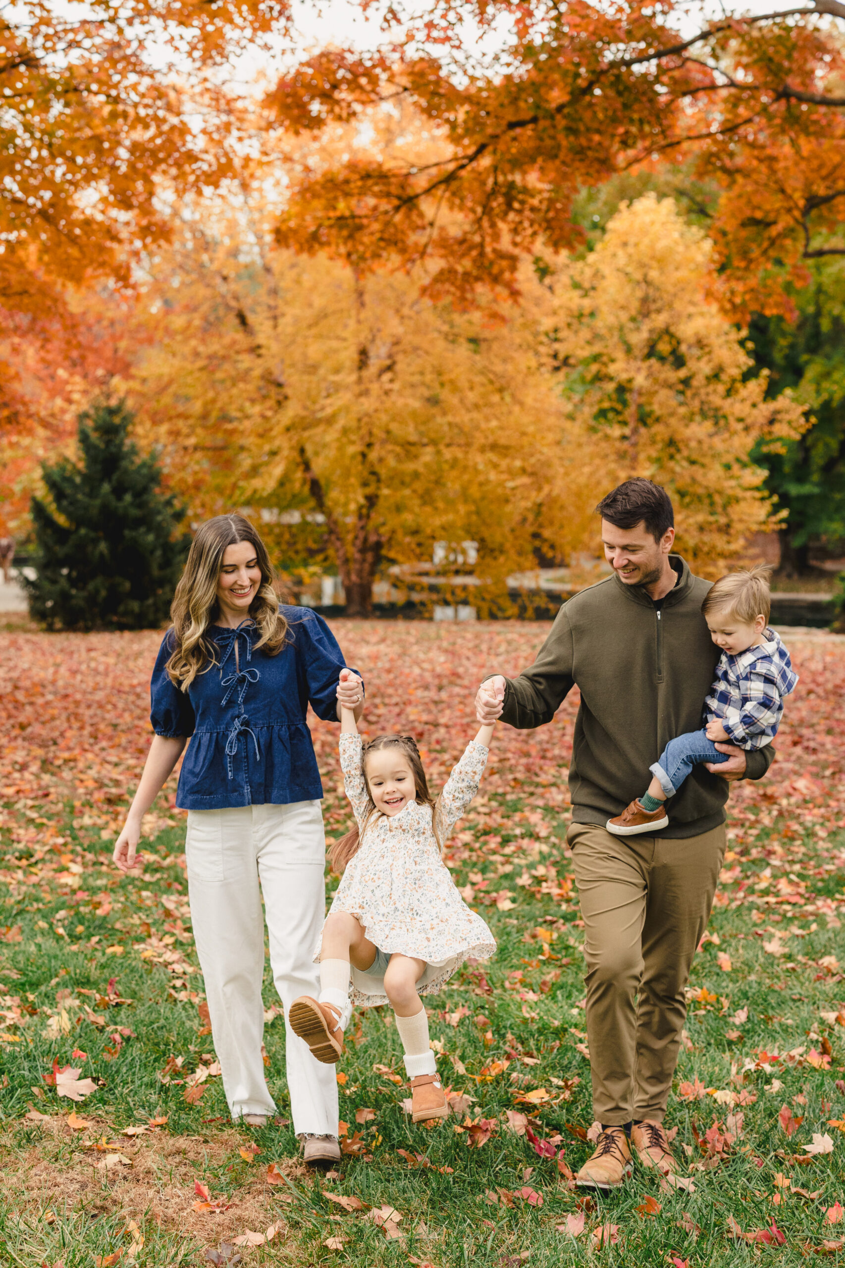 a mother, father, and their two children taking fall family photos in loose park in kansas city 