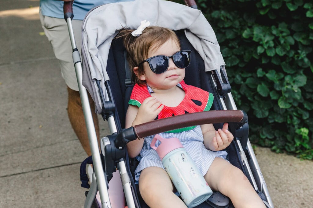 Toddler sporting sunglasses with a watermelon onesie.