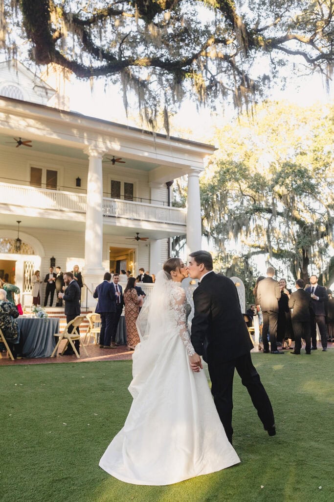 a bride and groom sharing a kiss in front of the Admiral's House in Charleston